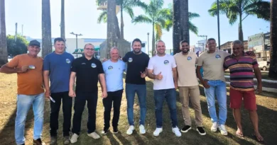Grupo de homens posa para foto ao ar livre em área com palmeiras