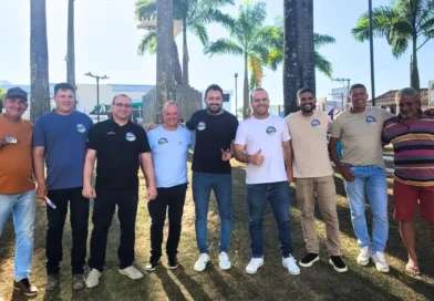 Grupo de homens posa para foto ao ar livre em área com palmeiras